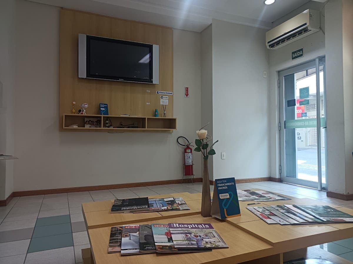 Recepção com mesa de revistas e TV no fundo, ambiente organizado.